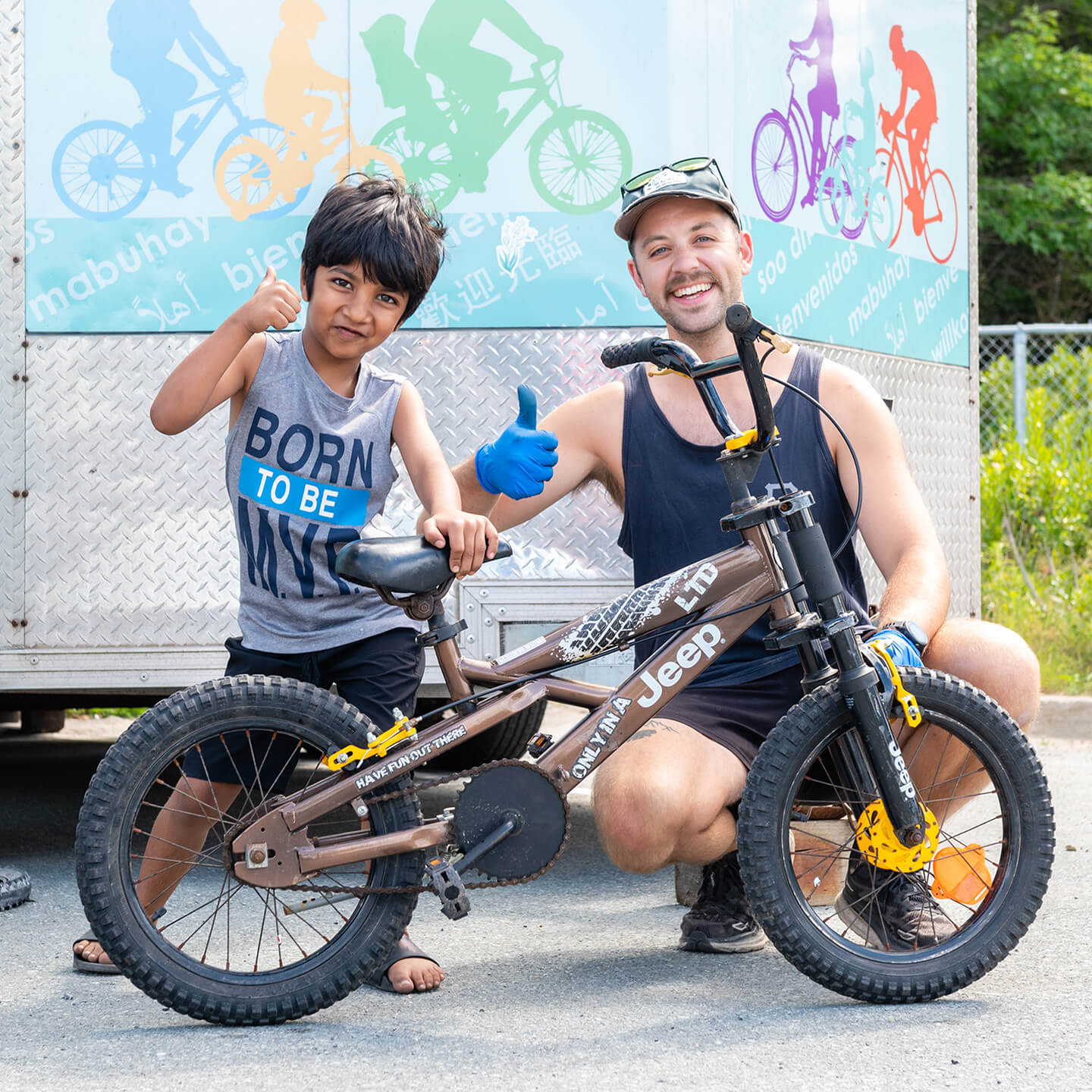 Young boy and staff giving a thumbs up, posing infront of a bicycle